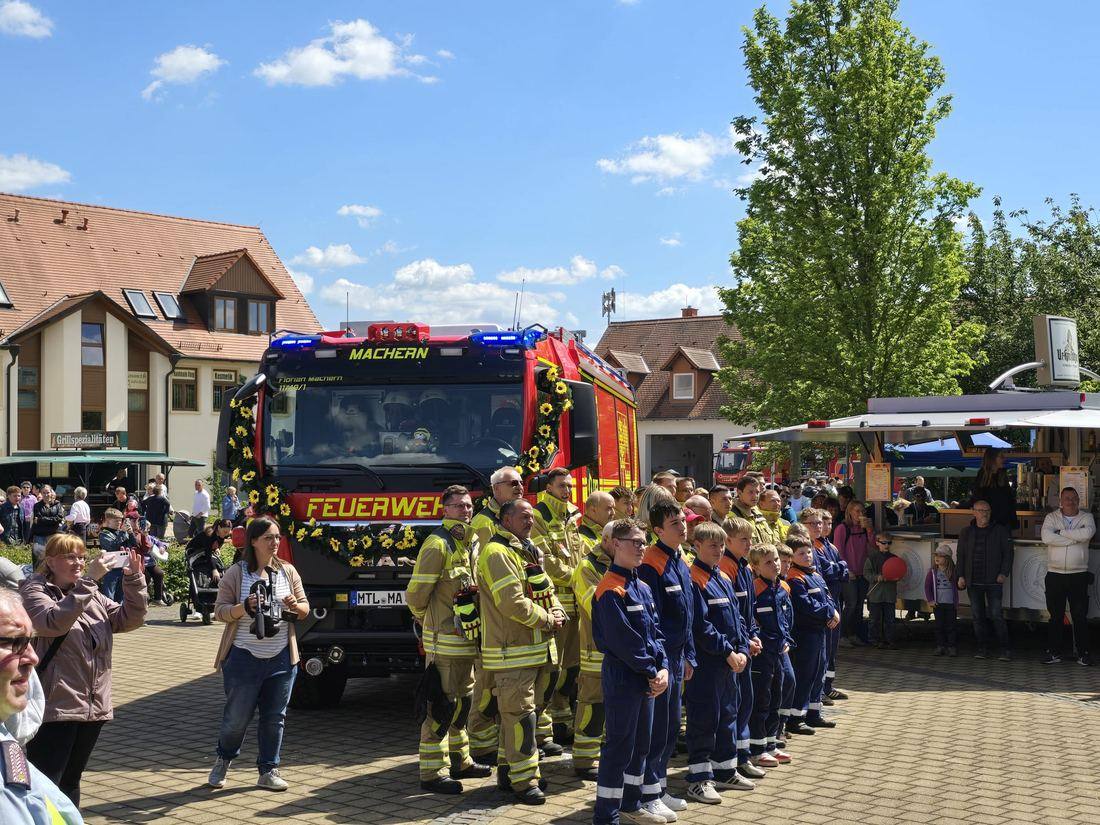 Das mit Sonnenblumen geschmückte HLF 20 beim Frühlingsfest, davor Einsatzabteilung und Jugendfeuerwehr