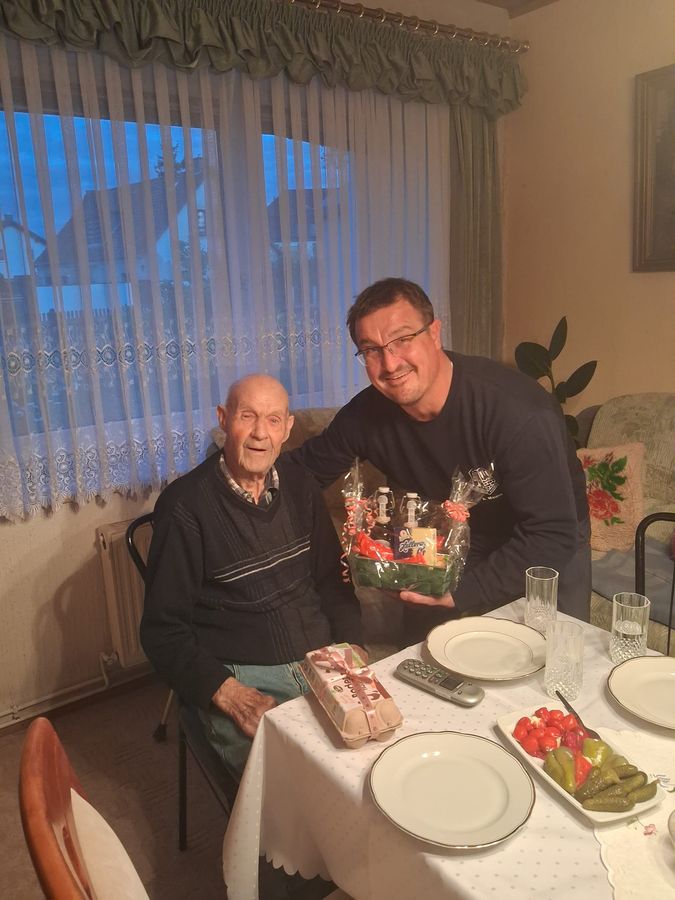 Der stellvertretende Wehrleiter Axel Maune überreicht Kamerad Arno Liepold einen Geschenkkorb zum 93. Geburtstag