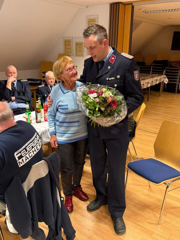 Ein Kamerad in Uniform überreicht einer Kameradin einen Blumenstrauß