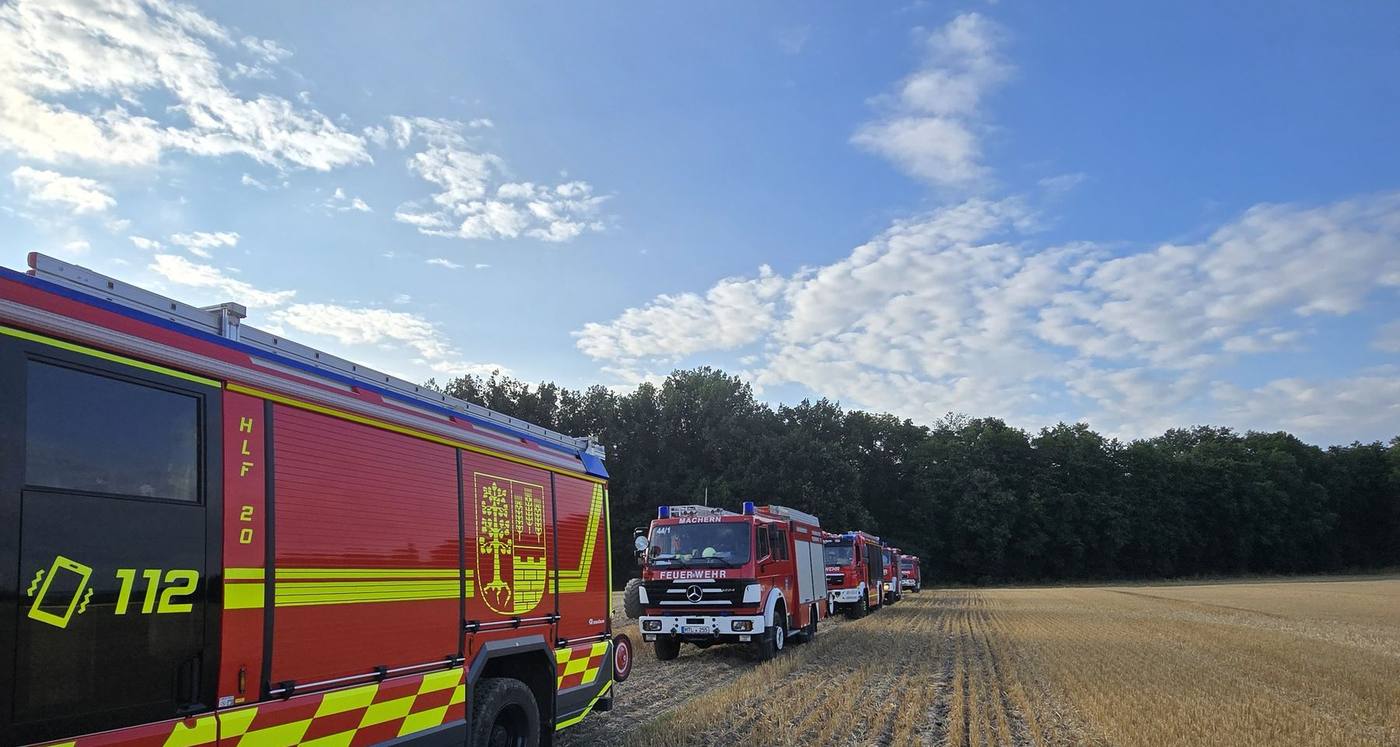 Fahrzeuge der Gemeindefeuerwehr Machern in einer Reihe am Rand eines Stoppelfelds