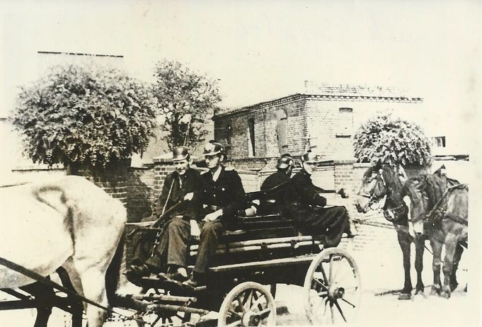 Feuerwehrmänner auf der Spritze von 1886 mit Pferdegespann