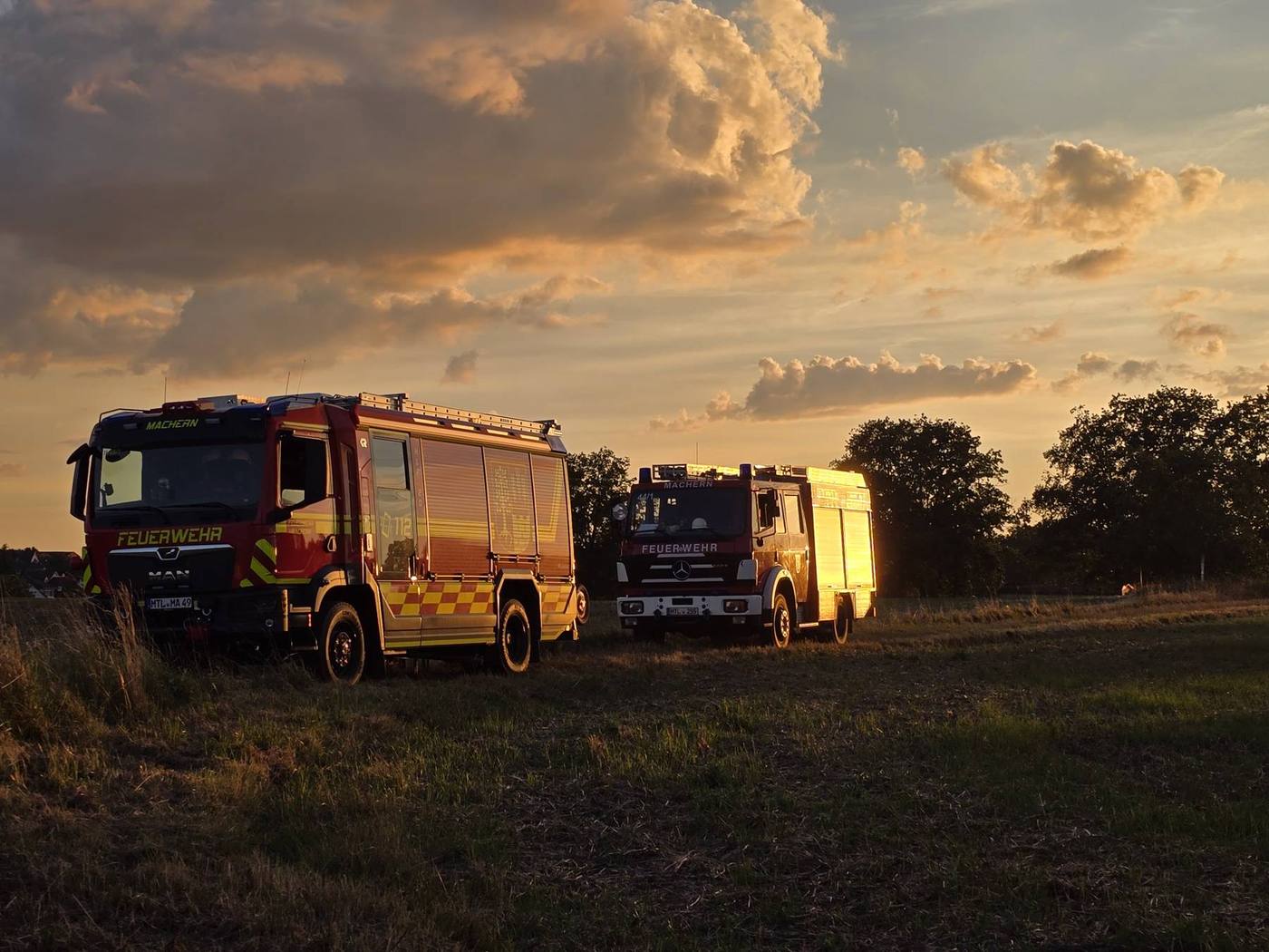 HLF 20 und LF 20 der Feuerwehr Machern im Abendlicht auf einem Feld