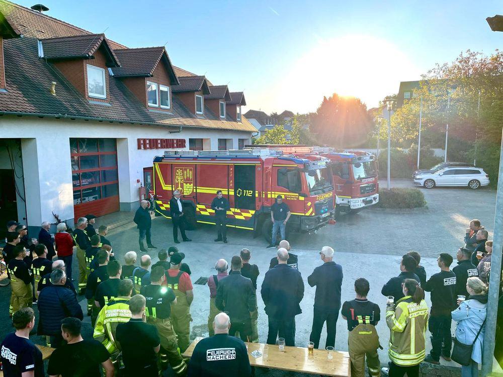 Viele Feuerwehrleute stehen im Halbkreis vor dem neuen HLF 20 am Gerätehaus
